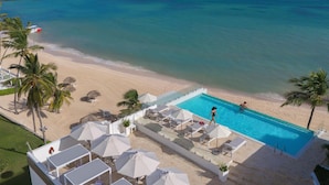 A poolside view with a beach and ocean, featuring lounge chairs and umbrellas. - HM Bavaro Beach – Adults Only (Punta Cana)