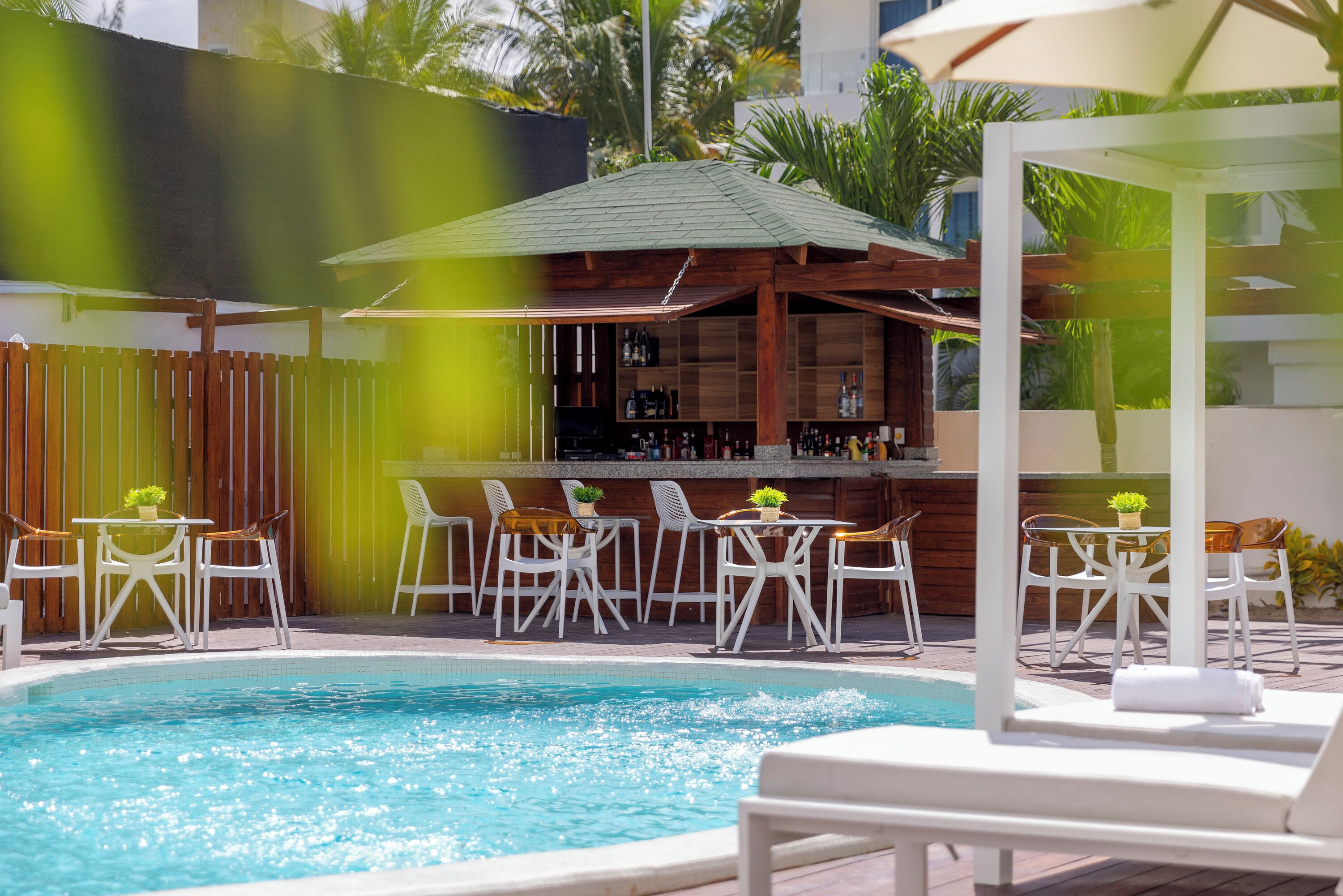 Un espace piscine avec des chaises longues et un bar.
