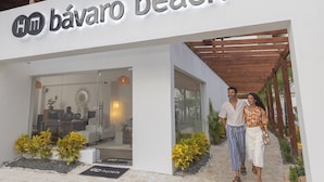 A hotel entrance with a modern design, a reception desk, and a glass facade. - HM Bavaro Beach – Adults Only (Punta Cana)