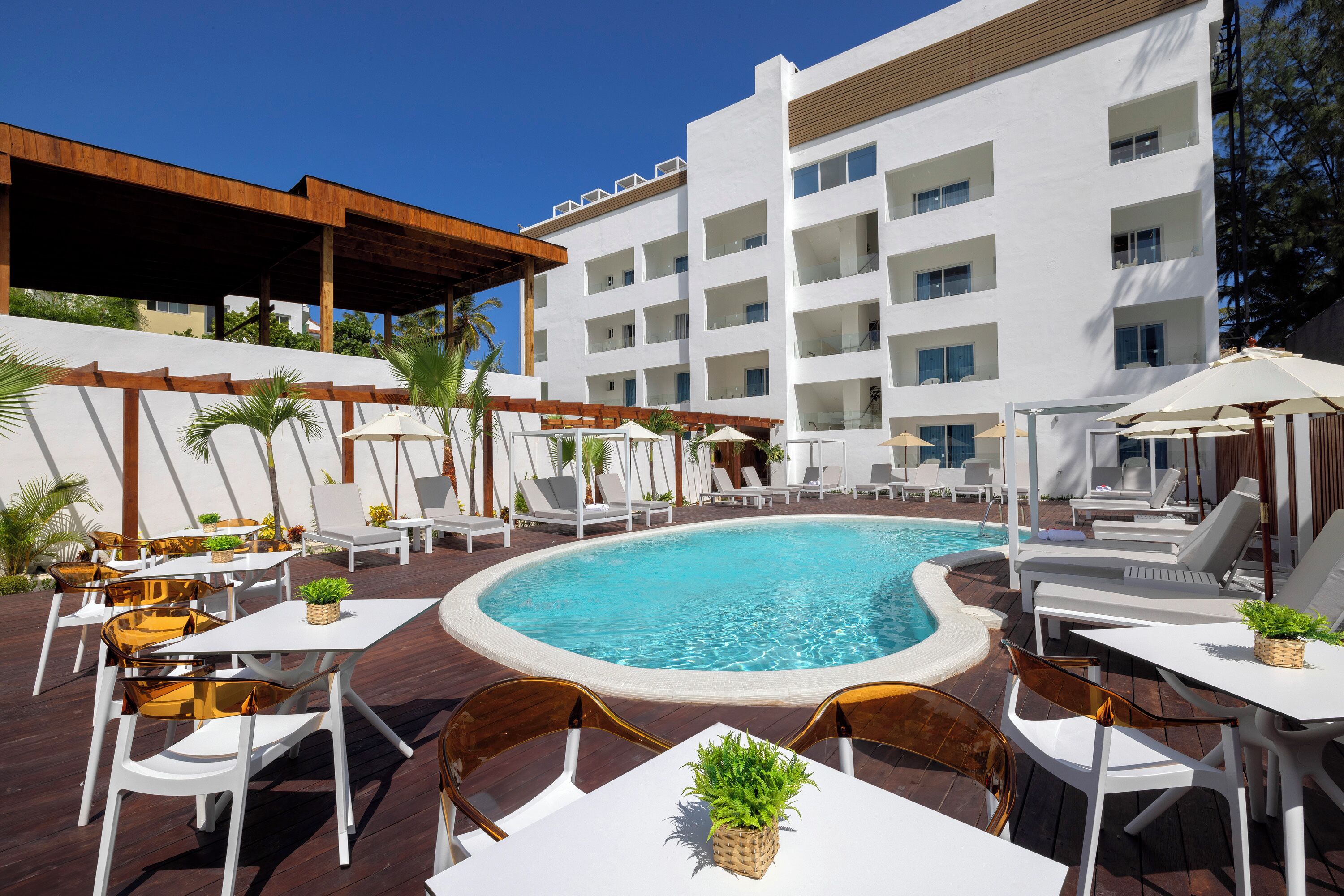 A poolside area with lounge chairs, tables, and a swimming pool.