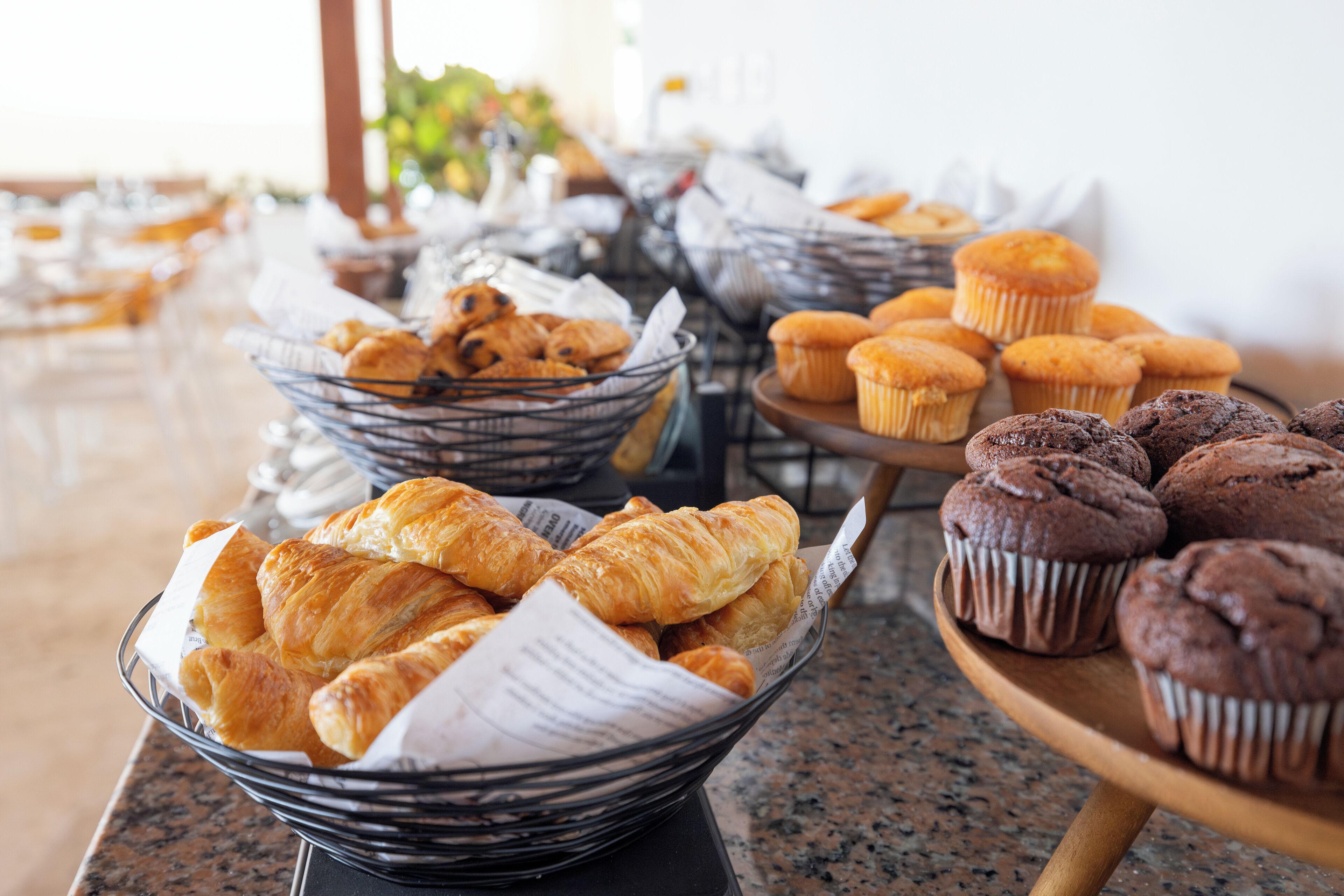 A buffet table with various baked goods including croissants, muffins, and pastries.