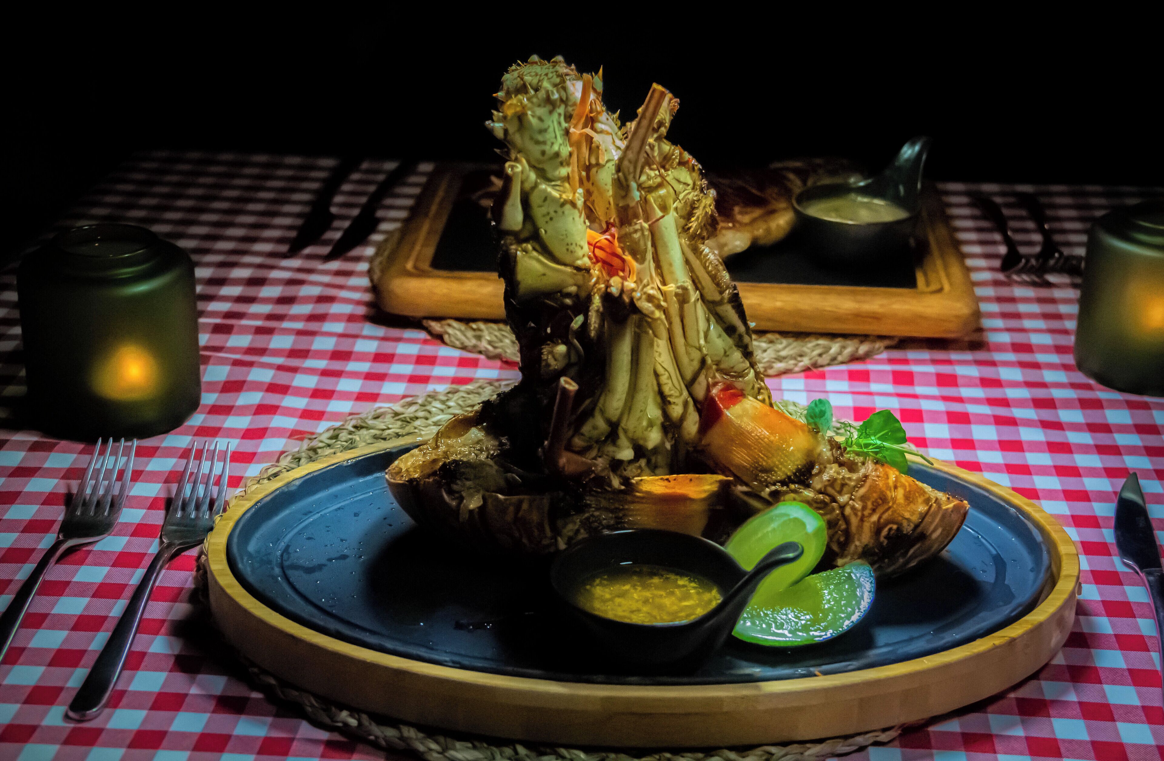 Un plat de fruits de mer servi sur une nappe à carreaux, accompagné d’un petit bol de sauce et d’un quartier de citron vert.