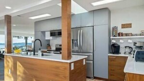 A modern kitchen with a central island, stainless steel appliances, and wooden accents. - 5BR/4BA: Spacious Step-Free Main Level, Relaxing Views, Next to Chamber Bay Golf (University Place)