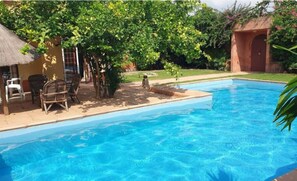 A swimming pool with a clear blue water surface, surrounded by a patio area with chairs and a small table. - Escale Saint-Louis Hôtel-Restaurant (St. Louis)