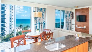 A modern kitchen with a large island, a dining area with wooden chairs, and a view of the ocean. - 504-505 International Resort 2 Bed 2 Ba 1600Sf Ocean View (Sunny Isles Beach)