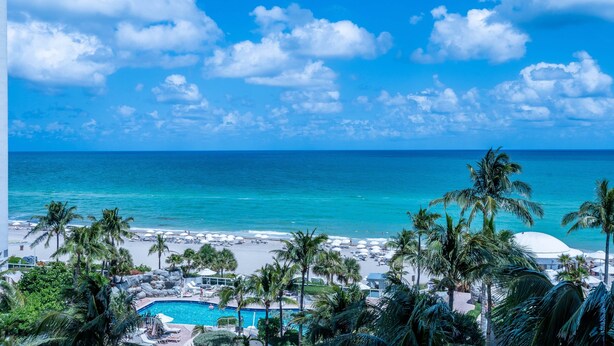 A beach resort with a pool, palm trees, and a view of the ocean. - 504-505 International Resort 2 Bed 2 Ba 1600Sf Ocean View (Sunny Isles Beach)