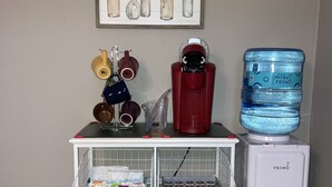 A kitchen area with a white refrigerator, a water dispenser, a coffee machine, and a small cart with checkered storage bins. - Quiet spacious home in Cul-de-sac near downtown (Tucson)