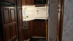 A compact kitchen with wooden cabinets, a microwave, and a sink. - Travel PR! (San Juan)