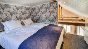 Un dormitorio con cama, un altillo de madera y una ventana.