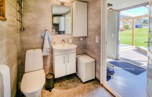 A bathroom with a toilet, sink, mirror, and a heater.
