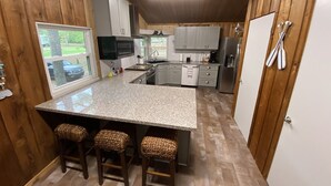 A compact kitchen with a central island, wooden flooring, and a view of the outdoors. - Shore Thing Waterfront Home with private covered boat dock on Toledo Bend (Hemphill)