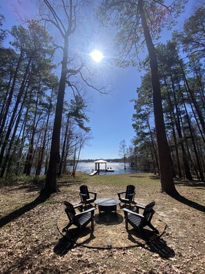 Un gazebo con vista su un lago, circondato da alberi alti e due poltrone Adirondack rivolte verso l'acqua.