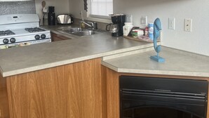 Een keuken met houten kastjes, een magnetron, fornuis, spoelbak en een vaatwasser.