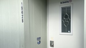 Een deur met een rookverbodssign, een codeerapparaat en een klein raam met decoratief ontwerp.