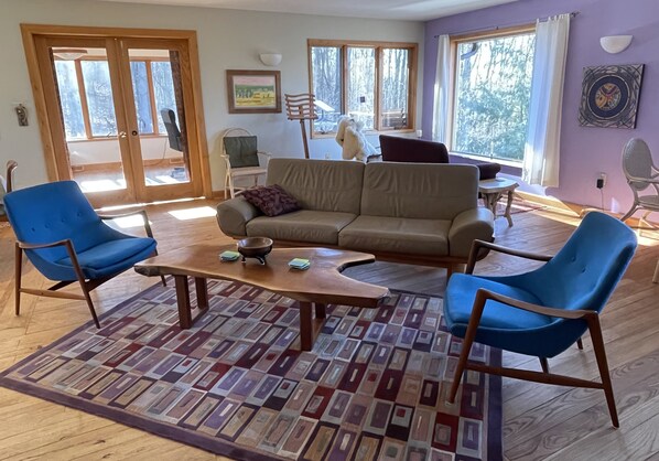 A living room with a sofa, two blue chairs, a coffee table, and a patterned rug. - Secluded Mid-Century 10 minutes from Devils Lake State Park, Baraboo & skiing (Baraboo)