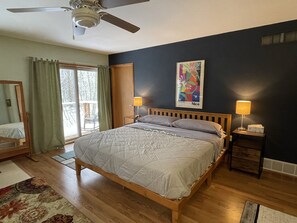 A bedroom with a bed, two bedside lamps, a ceiling fan, a window with curtains, and a painting on the wall. - Secluded Mid-Century 10 minutes from Devils Lake State Park, Baraboo & skiing (Baraboo)