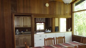 Un intérieur en bois comprenant un coin cuisine, une table à manger et des chaises.