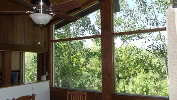 Une pièce dotée de grandes fenêtres, d’un ventilateur de plafond et de meubles en bois.