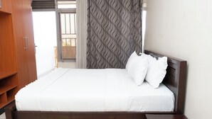 A neatly made bed with white bedding, a wooden headboard, and a small wooden nightstand beside it.
