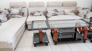 A modern living room with a sofa set, a glass coffee table, and a side table.