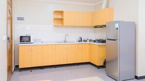 A kitchen with wooden cabinets, a microwave, a sink, and a refrigerator.