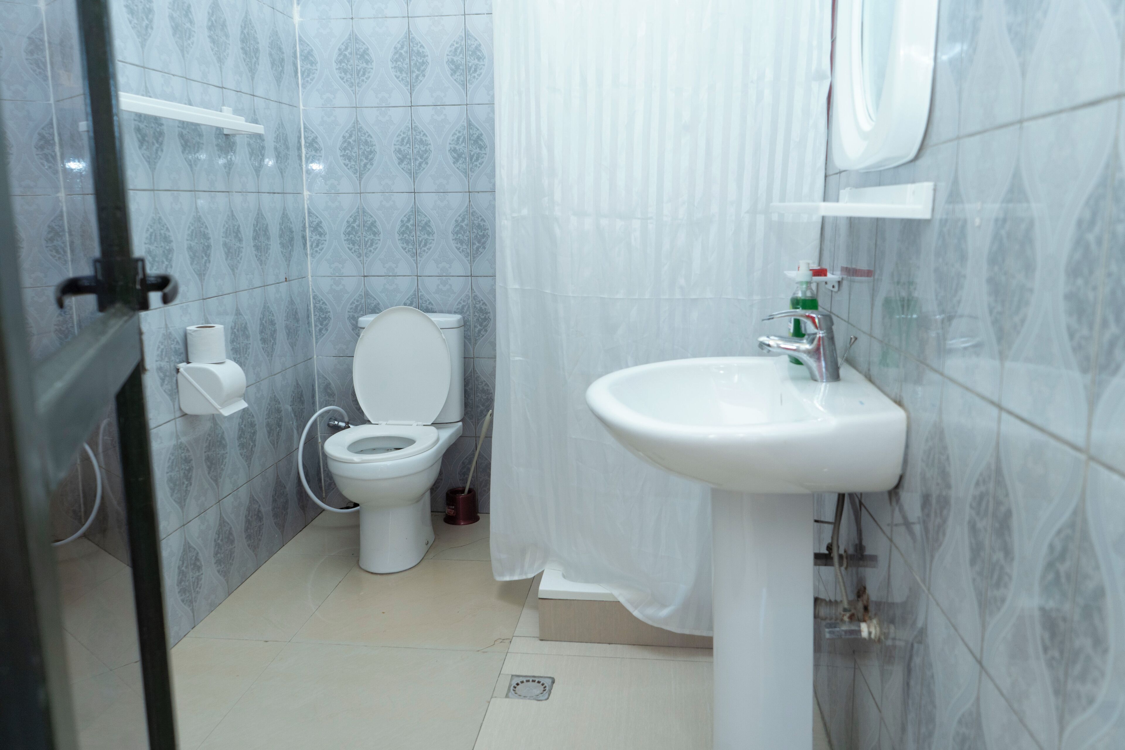 A bathroom with a toilet, sink, and shower curtain.