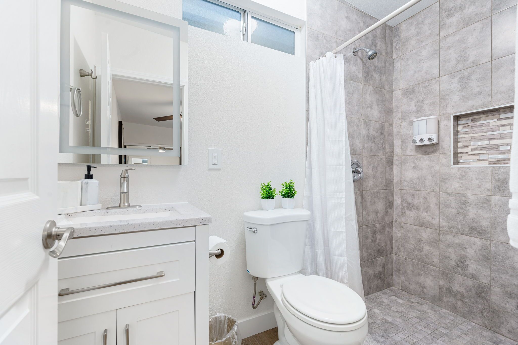 A modern bathroom with a toilet, sink, and shower.