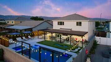 A modern house with a swimming pool, outdoor seating, and a patio area.