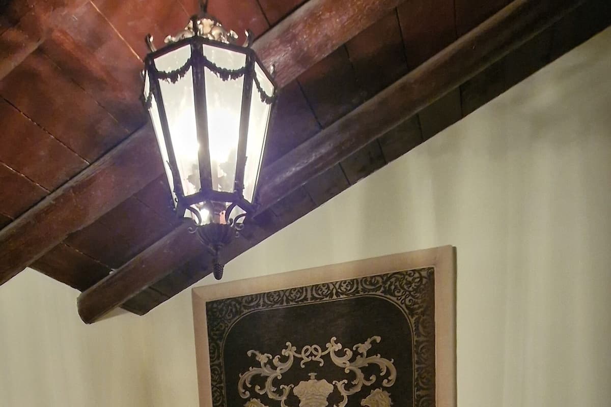 Un dormitorio con cama, cabecera decorativa, lámpara colgante y una mesita de noche.