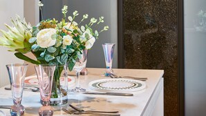 Et spisebord dækket med tallerkener, bestik og en vase med blomster.