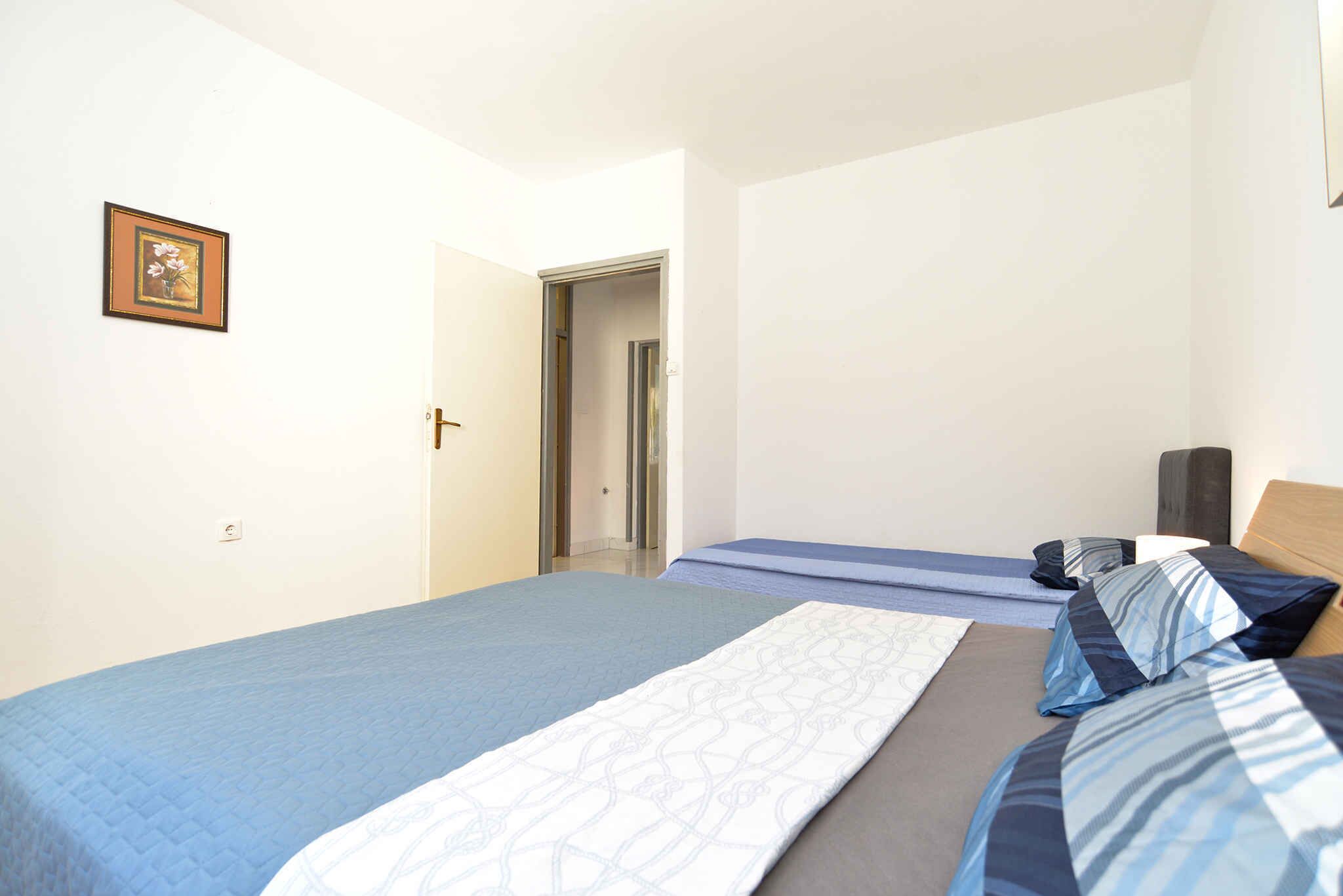Une chambre à coucher comprenant un lit, une table de chevet, une lampe et une porte donnant sur une autre pièce.