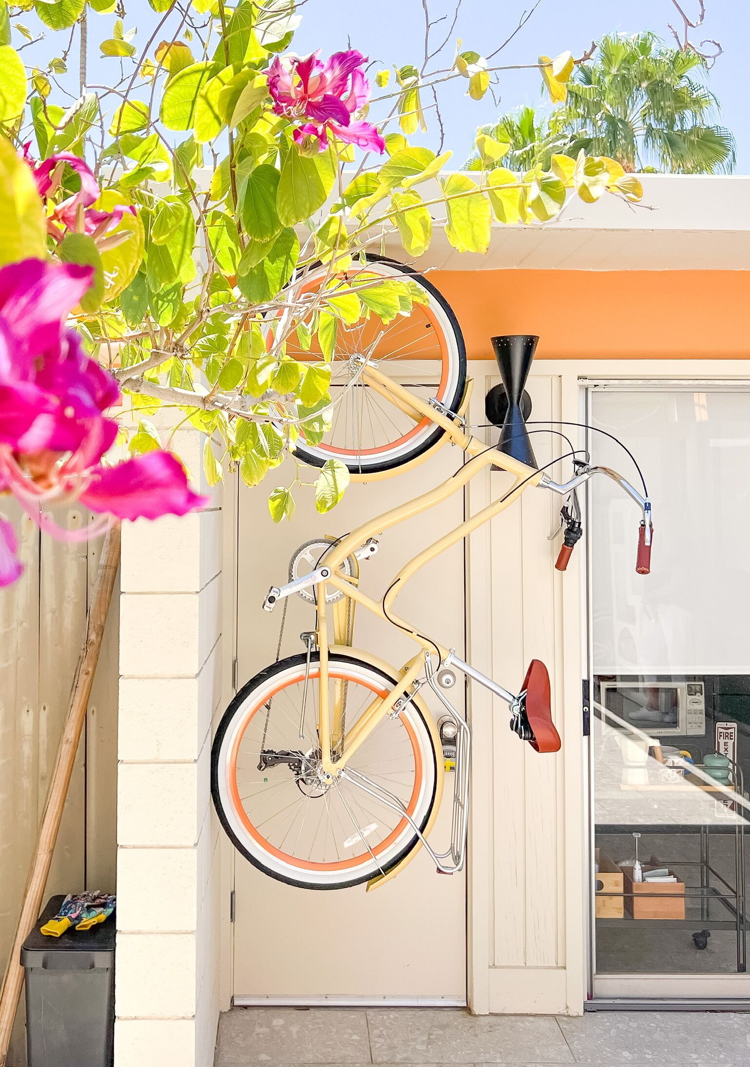 Una bicicleta recolzada contra una paret, amb una porta i una finestra al fons.