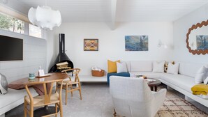 A modern living room with a fireplace, white furniture, and artwork on the walls. - New to VRBO! MidCentury Modern Bungalow @ Ocotillo Lodge (Palm Springs)