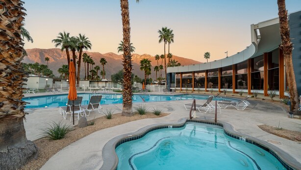 A pool area with lounge chairs, palm trees, and a modern building with large windows. - New to VRBO! MidCentury Modern Bungalow @ Ocotillo Lodge (Palm Springs)