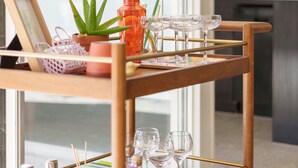 A wooden cart with various items including a green box, a potted plant, and several glasses. - New to VRBO! MidCentury Modern Bungalow @ Ocotillo Lodge (Palm Springs)