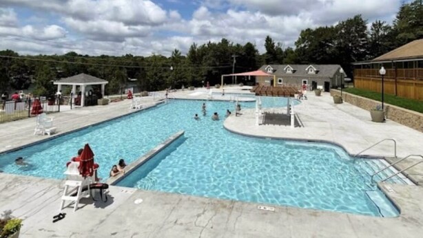 A swimming pool with multiple lanes, a gazebo, and lounge chairs.