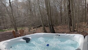 A hot tub with a digital temperature gauge, surrounded by a wooded area.