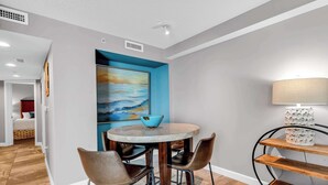 A dining area with a round table, four chairs, a blue bowl, a lamp, and a painting on the wall. - Oceanfront Perfect Couples Getaway (Myrtle Beach)