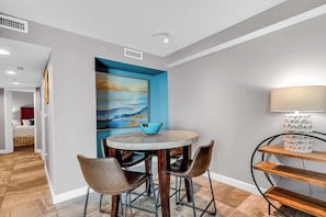 A dining area with a round table, four chairs, a blue bowl, a lamp, and a painting on the wall. - Oceanfront Perfect Couples Getaway (Myrtle Beach)