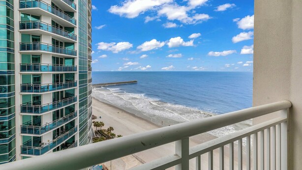 A high-rise hotel with multiple balconies overlooking a beach and ocean. - Oceanfront Perfect Couples Getaway (Myrtle Beach)