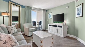 A living room with a sofa, armchair, TV, and a cabinet. - Sandy Beach Resort 1705 - Oceanfront Views (Myrtle Beach)