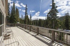 A wooden deck with chairs, surrounded by tall trees and a mountain in the background. - Breathtaking Breckenridge Mountain Escape (Breckenridge)
