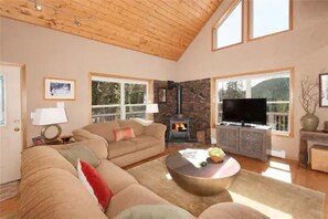 A spacious living room with a large sofa, a coffee table, a fireplace, and a television. - Breathtaking Breckenridge Mountain Escape (Breckenridge)