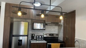 A modern kitchen with stainless steel appliances, wooden cabinets, and pendant lighting. - Apartment in Ecohousing Phase 2 (Tegucigalpa)