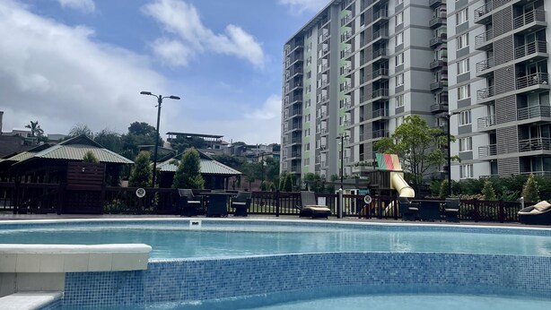 A swimming pool with a hot tub, surrounded by a fence, and adjacent to a tall residential building. - Apartment in Ecohousing Phase 2 (Tegucigalpa)
