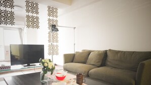 Una sala de estar con sofá, mesa de centro, televisor y paneles decorativos en la pared.