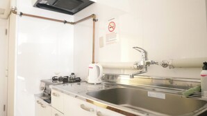 Una cocina moderna con un lavamanos de acero inoxidable, hervidor y cafetera.