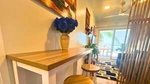 Un coin bar avec un comptoir en bois, deux tabourets et un vase de roses bleues.