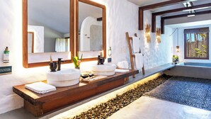 A modern bathroom with a large mirror, two sinks, a wooden vanity, and a pebble-lined floor. - Reserva Jacumã Boutique Hotel  (Porto Seguro)