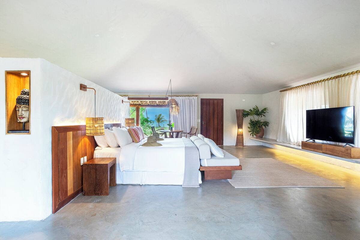 A modern living room with a large sectional sofa, a flat-screen TV, and a dining area with a table and chairs.